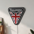 Unlit Triumph LED lightbox mounted on a wall in daylight