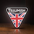 Front view of Triumph LED lightbox sign glowing on a wooden desk