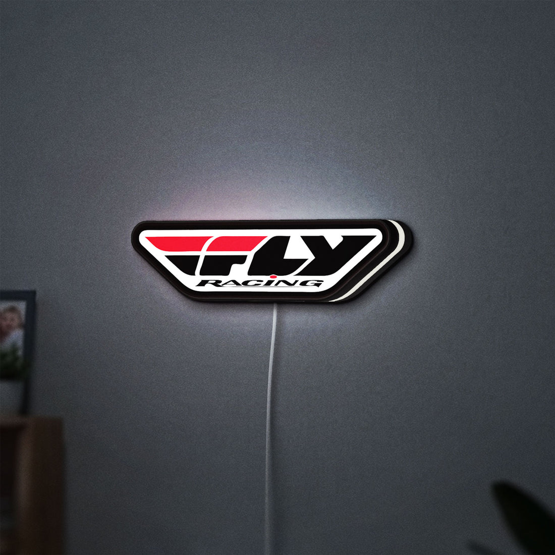 Fly Racing LED lightbox hanging on a wall with white glow