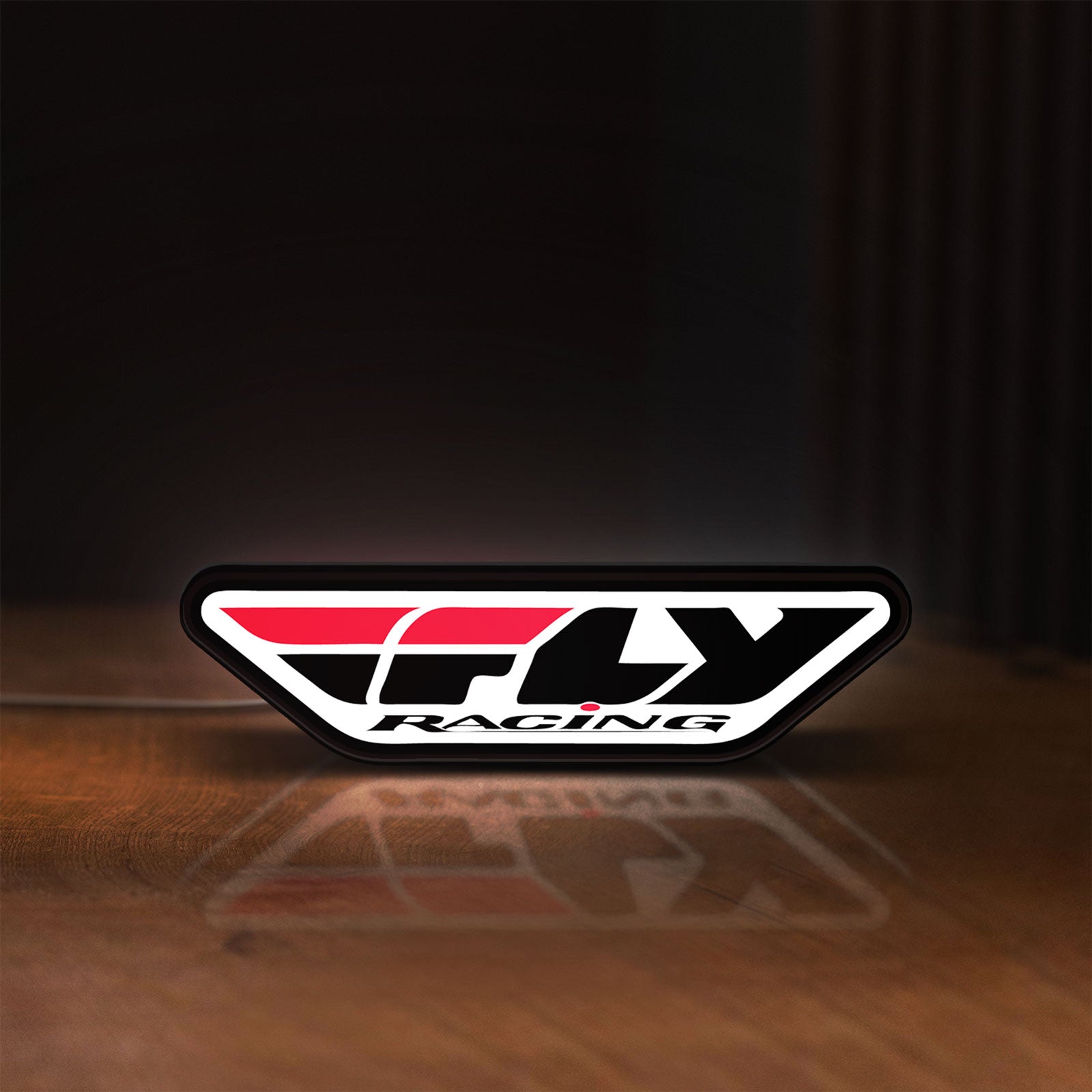 Front view of Fly Racing LED lightbox sign glowing on a wooden desk