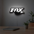 FOX Racing LED lightbox hanging on a room wall with soft white light