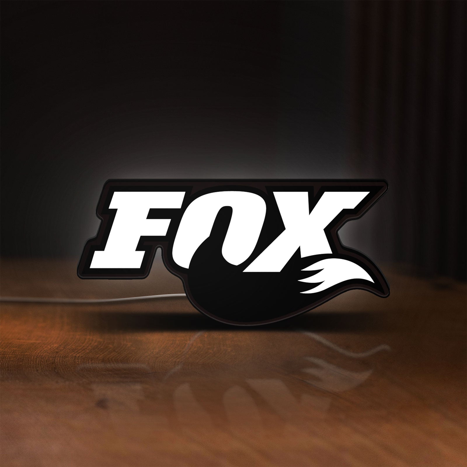 Front view of FOX Racing LED lightbox sign glowing on a wooden desk