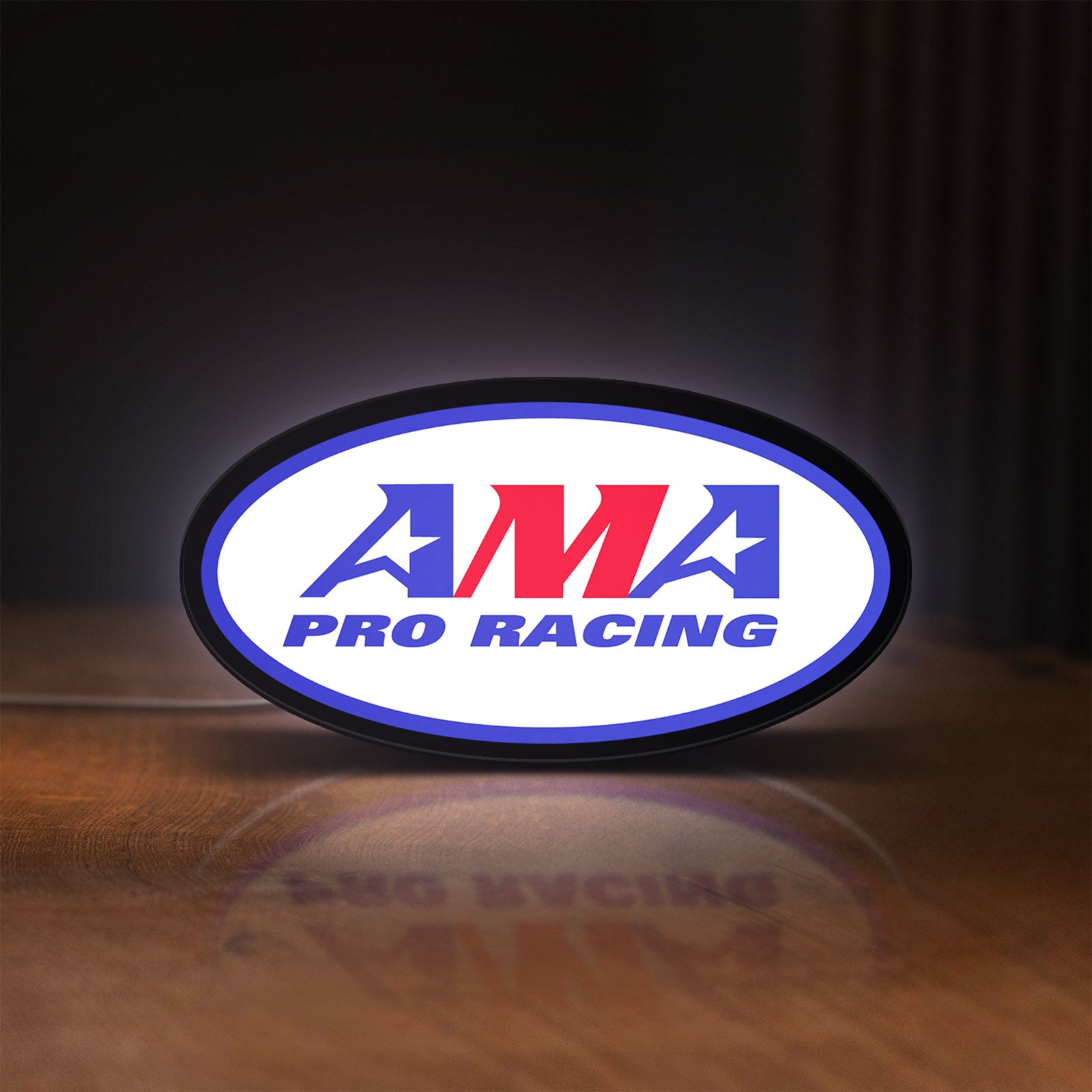 Front view of AMA Pro Racing LED lightbox sign glowing on a wooden desk