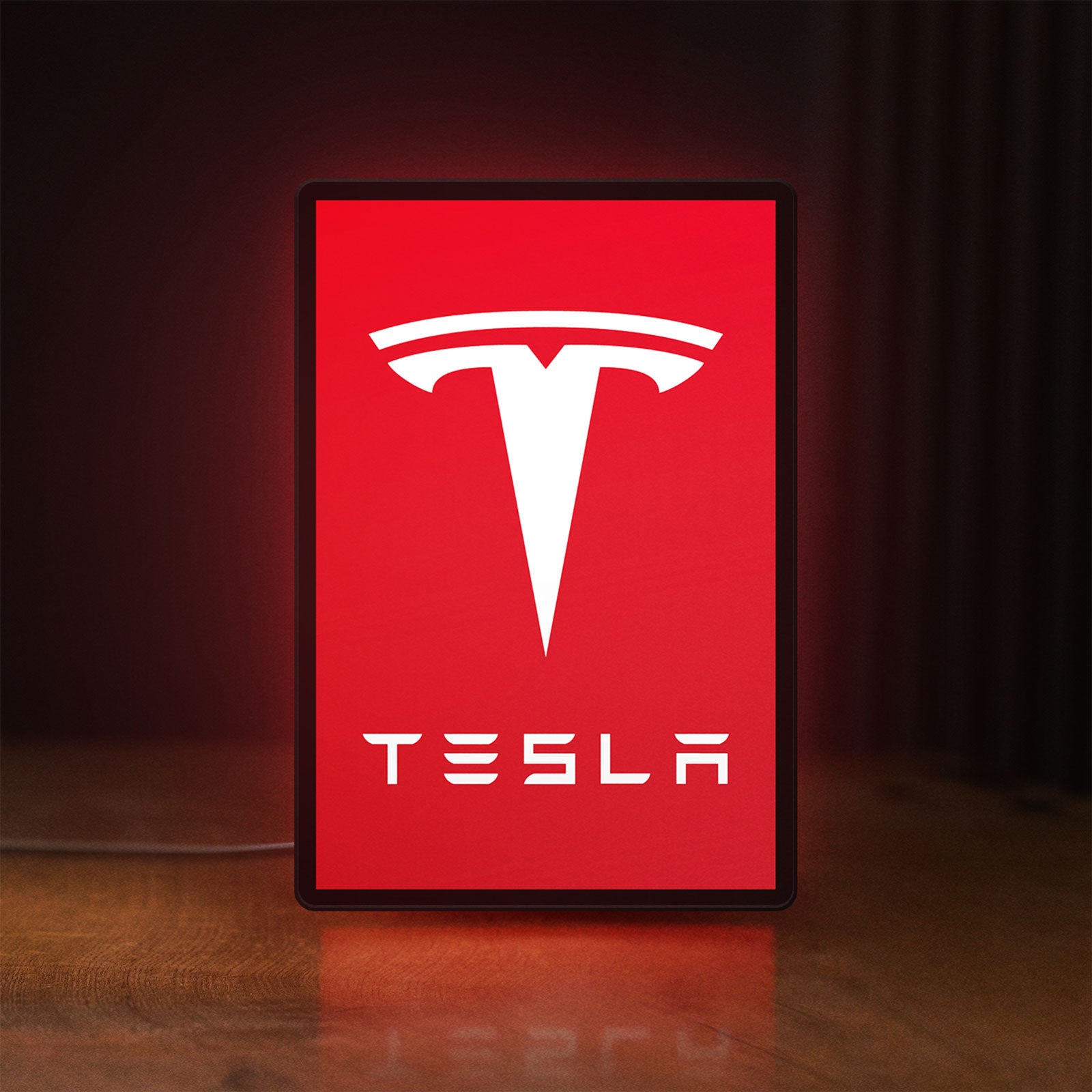 Front view of Tesla LED lightbox sign glowing on a wooden desk
