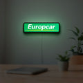 Europcar Sign LED lightbox hanging on a room wall with soft green light
