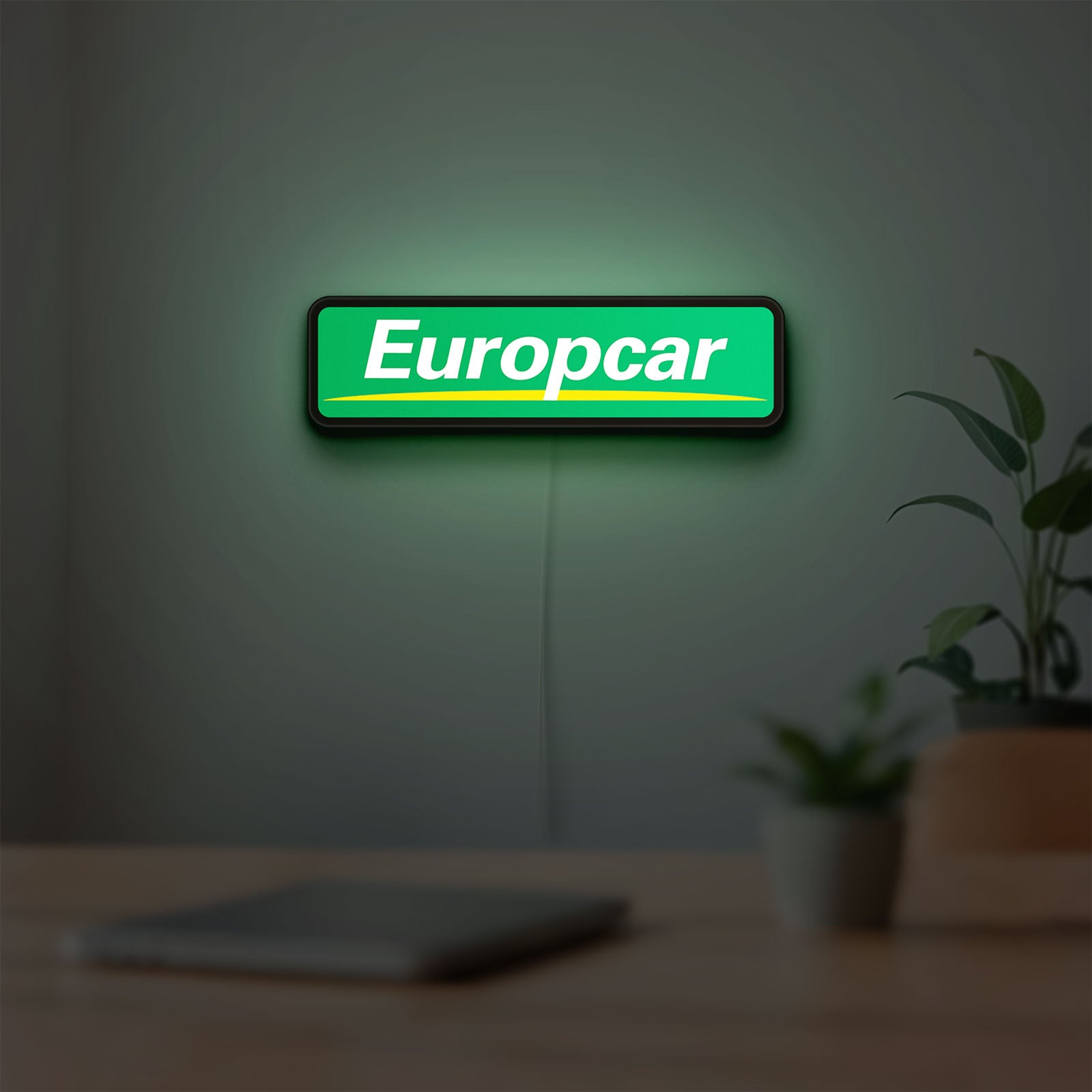 Europcar Sign LED lightbox hanging on a room wall with soft green light