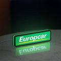 Europcar Sign LED lightbox standing on a desk from an angled side view with green glow