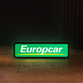 Front view of Europcar Sign LED lightbox sign glowing on a wooden desk