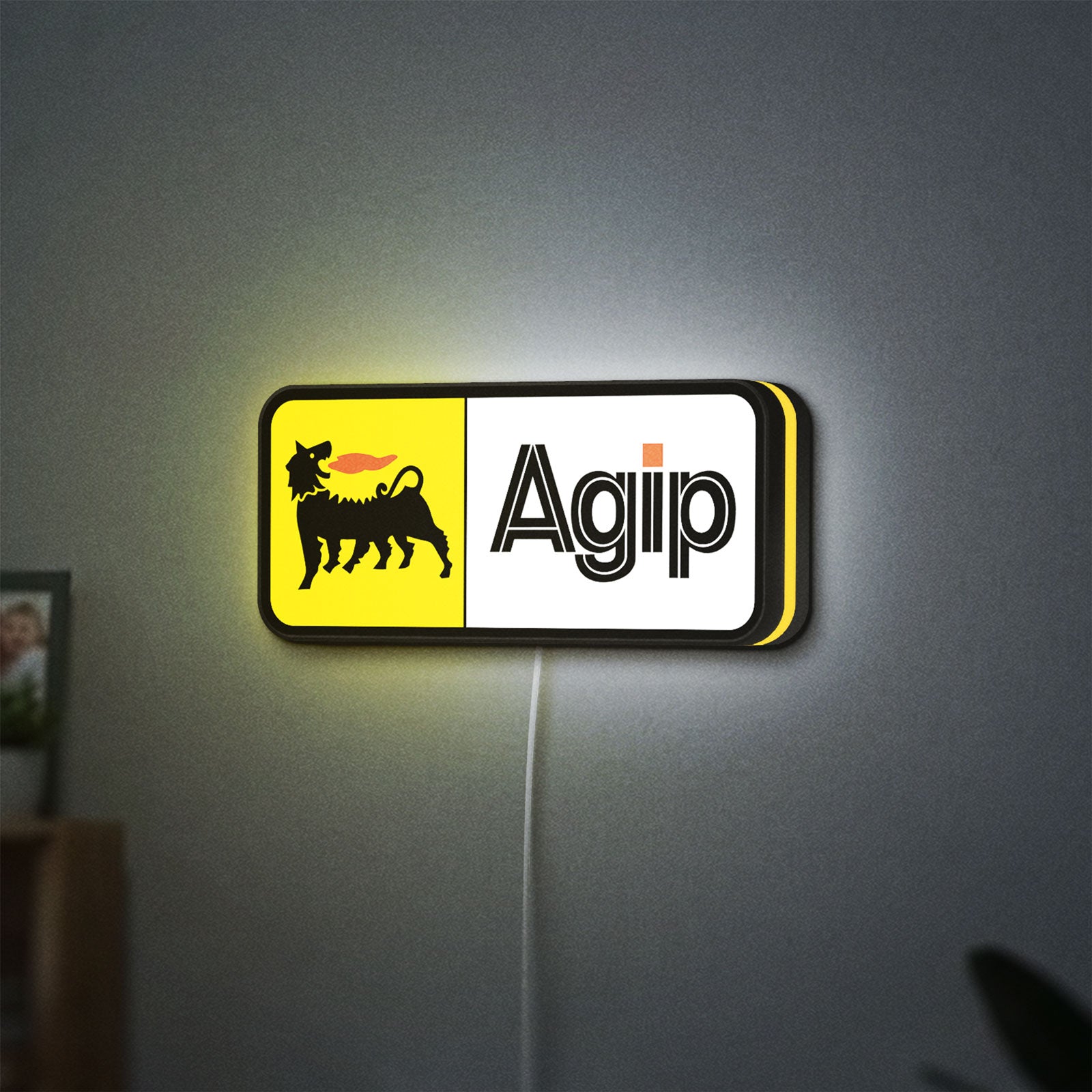 Agip Six-Legged Dog LED lightbox hanging on a wall with yellow glow