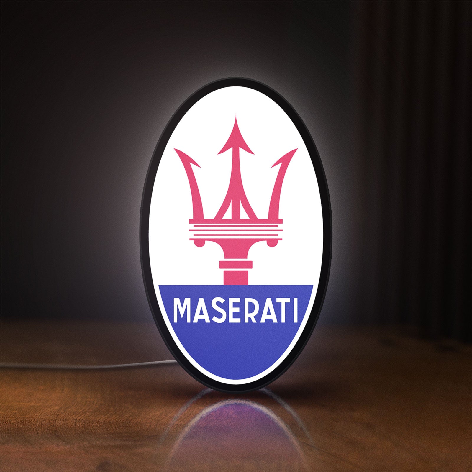 Front view of Maserati LED lightbox sign glowing on a wooden desk