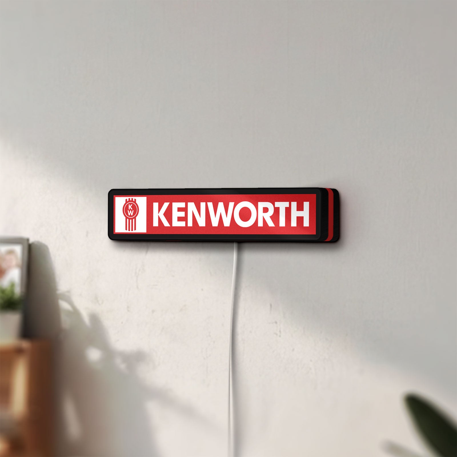 Unlit Kenworth LED lightbox mounted on a wall in daylight