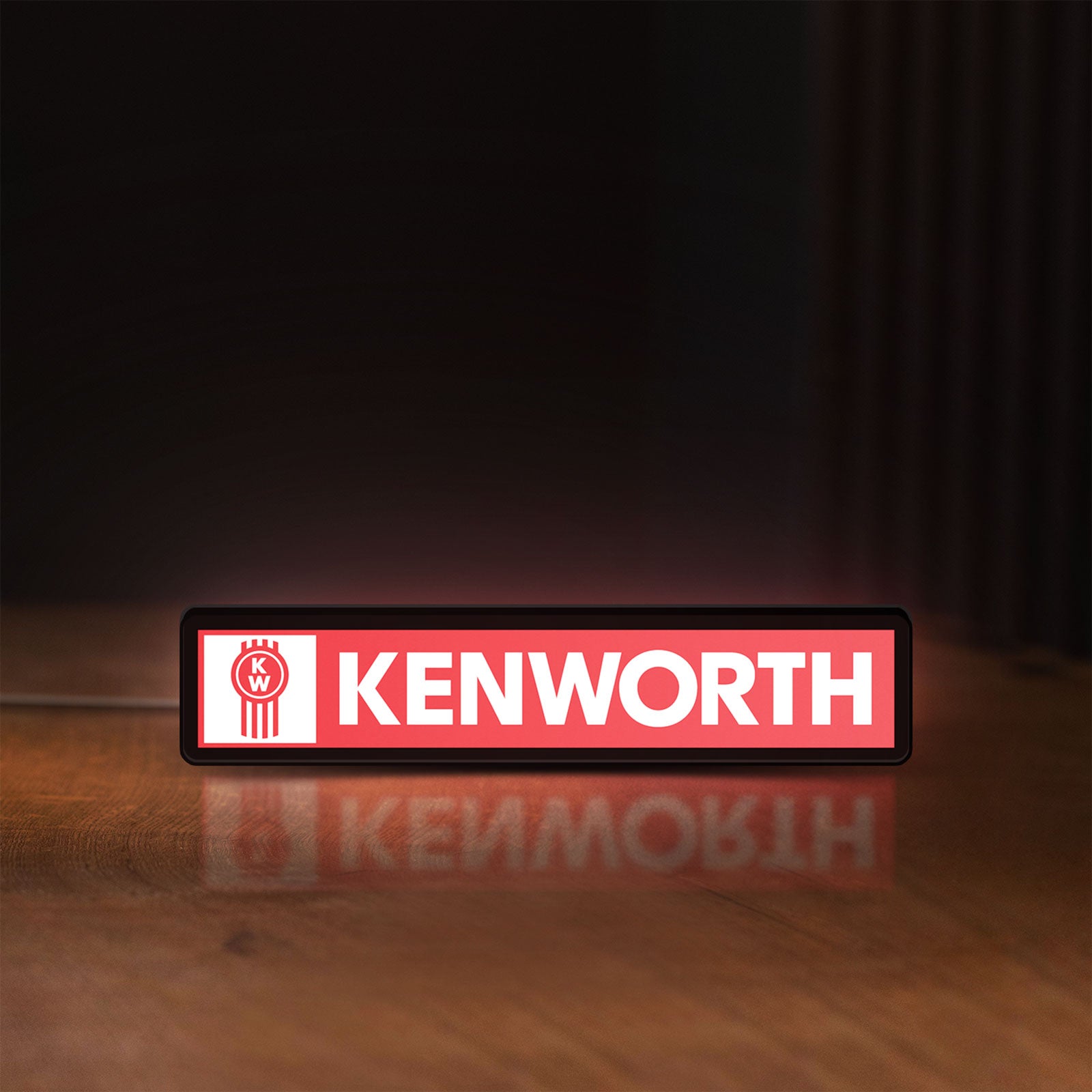 Front view of Kenworth LED lightbox sign glowing on a wooden desk