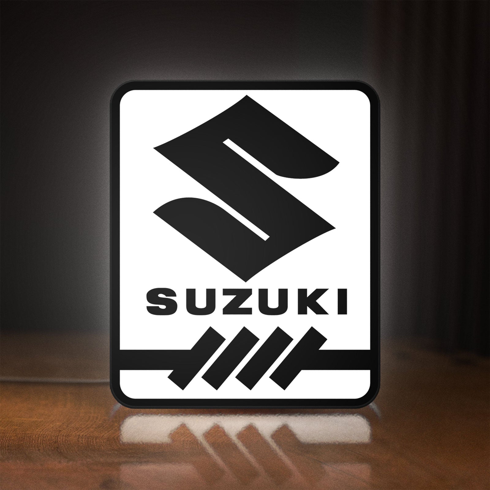 Front view of Suzuki LED lightbox sign glowing on a wooden desk