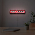 Overhaulin LED lightbox hanging on a room wall with soft red light