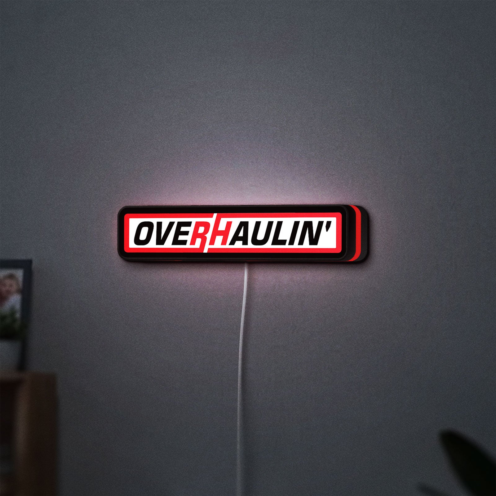Overhaulin LED lightbox hanging on a wall with red glow