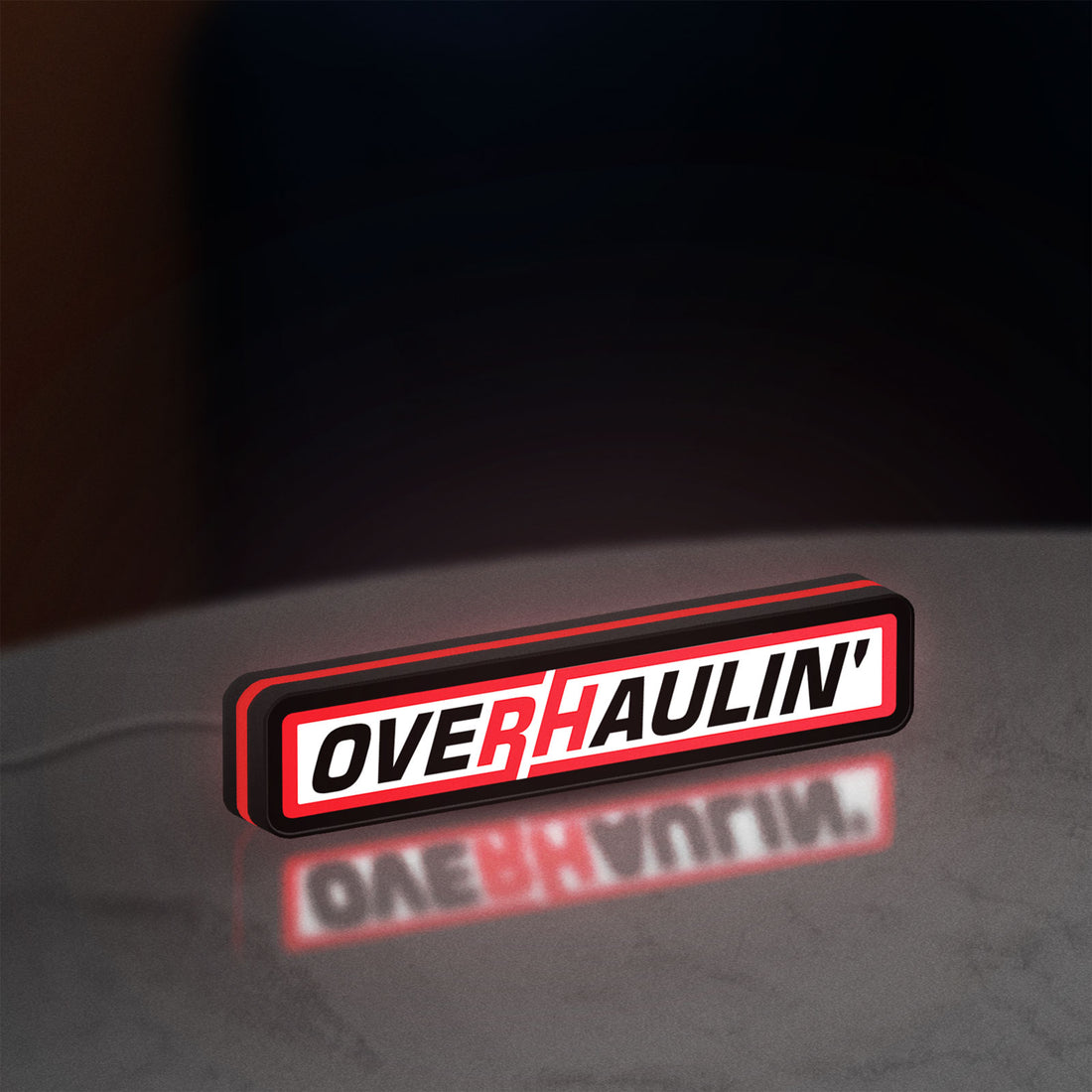 Overhaulin LED lightbox hanging on a wall with red glow