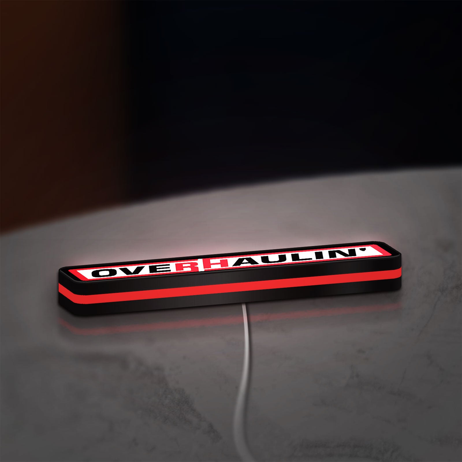 Overhaulin LED lightbox lying flat on a desk with red glow