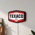 Unlit Texaco LED lightbox mounted on a wall in daylight