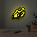 Ting'Avert Moto LED lightbox hanging on a room wall with soft yellow light