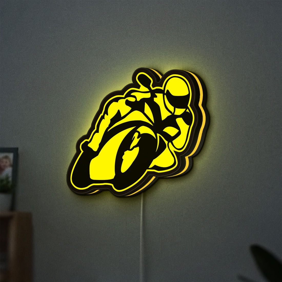 Ting'Avert Moto LED lightbox hanging on a wall with yellow glow