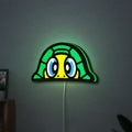 TURTLE ROSSI LED lightbox hanging on a wall with green glow