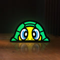 Front view of TURTLE ROSSI LED lightbox sign glowing on a wooden desk