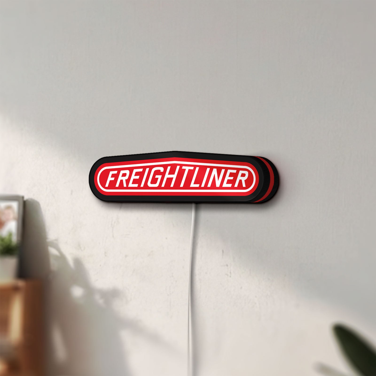Unlit Freightliner Trucks LED lightbox mounted on a wall in daylight