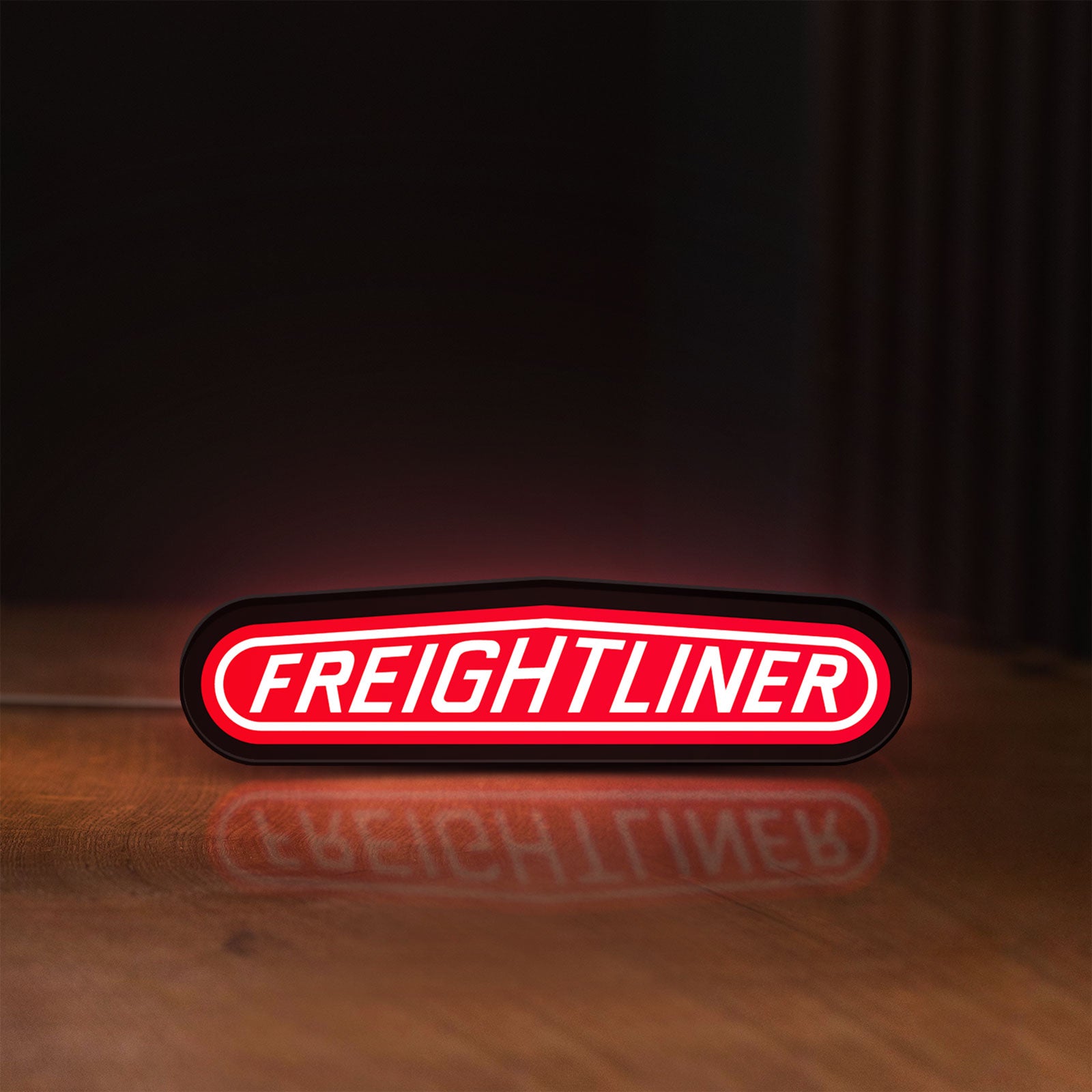 Front view of Freightliner Trucks LED lightbox sign glowing on a wooden desk