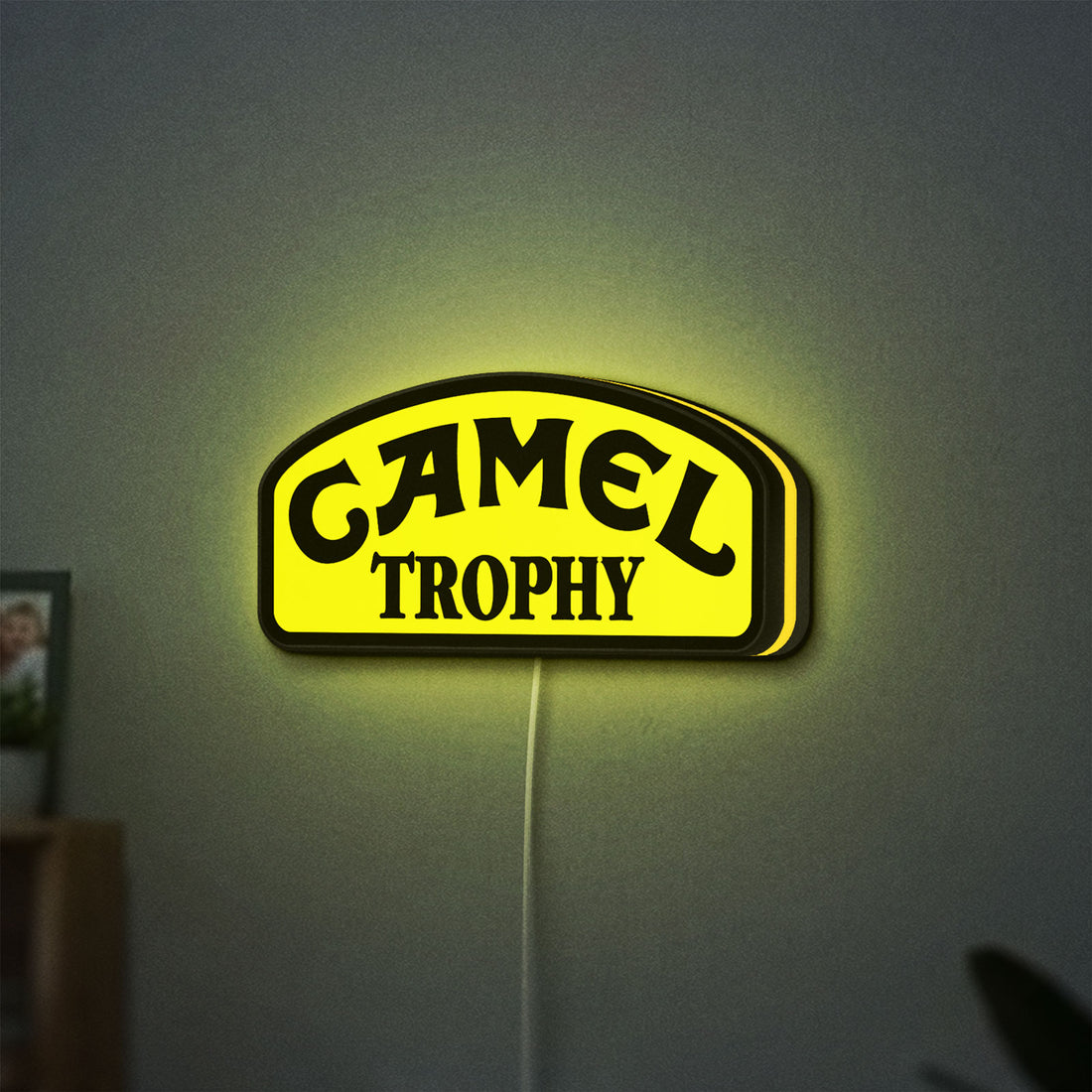Camel Trophy LED lightbox hanging on a wall with yellow glow