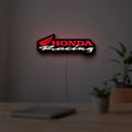 Honda Racing LED lightbox hanging on a room wall with soft red light