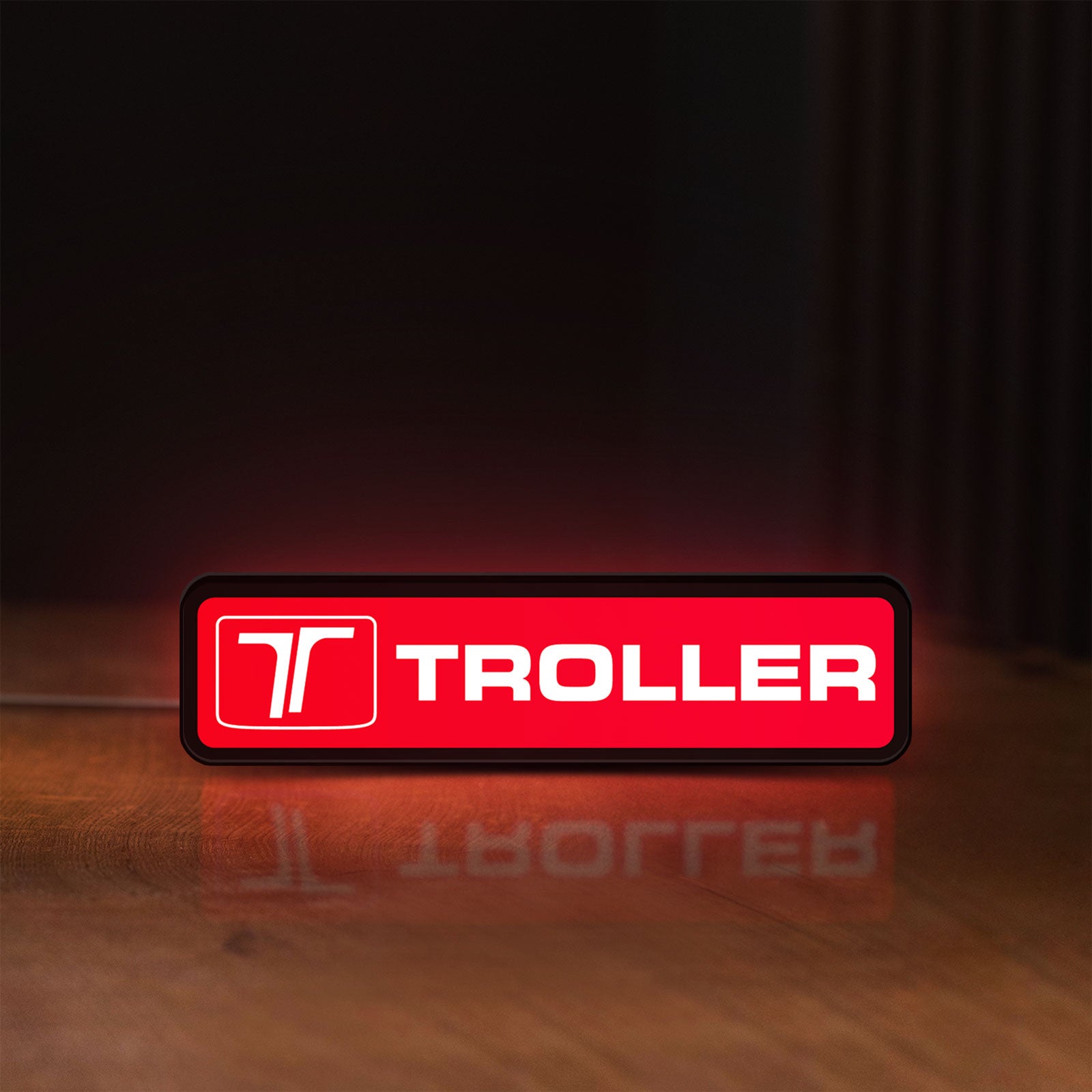 Front view of Troller LED lightbox sign glowing on a wooden desk