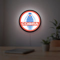 Cobra LED lightbox hanging on a room wall with soft red light
