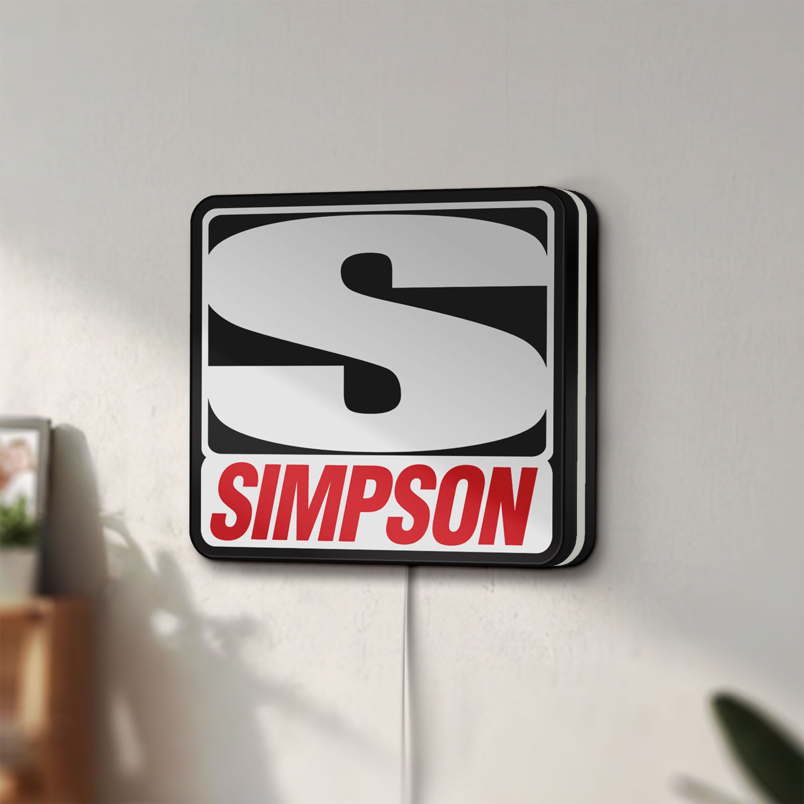 Unlit Simpson Racing LED lightbox mounted on a wall in daylight