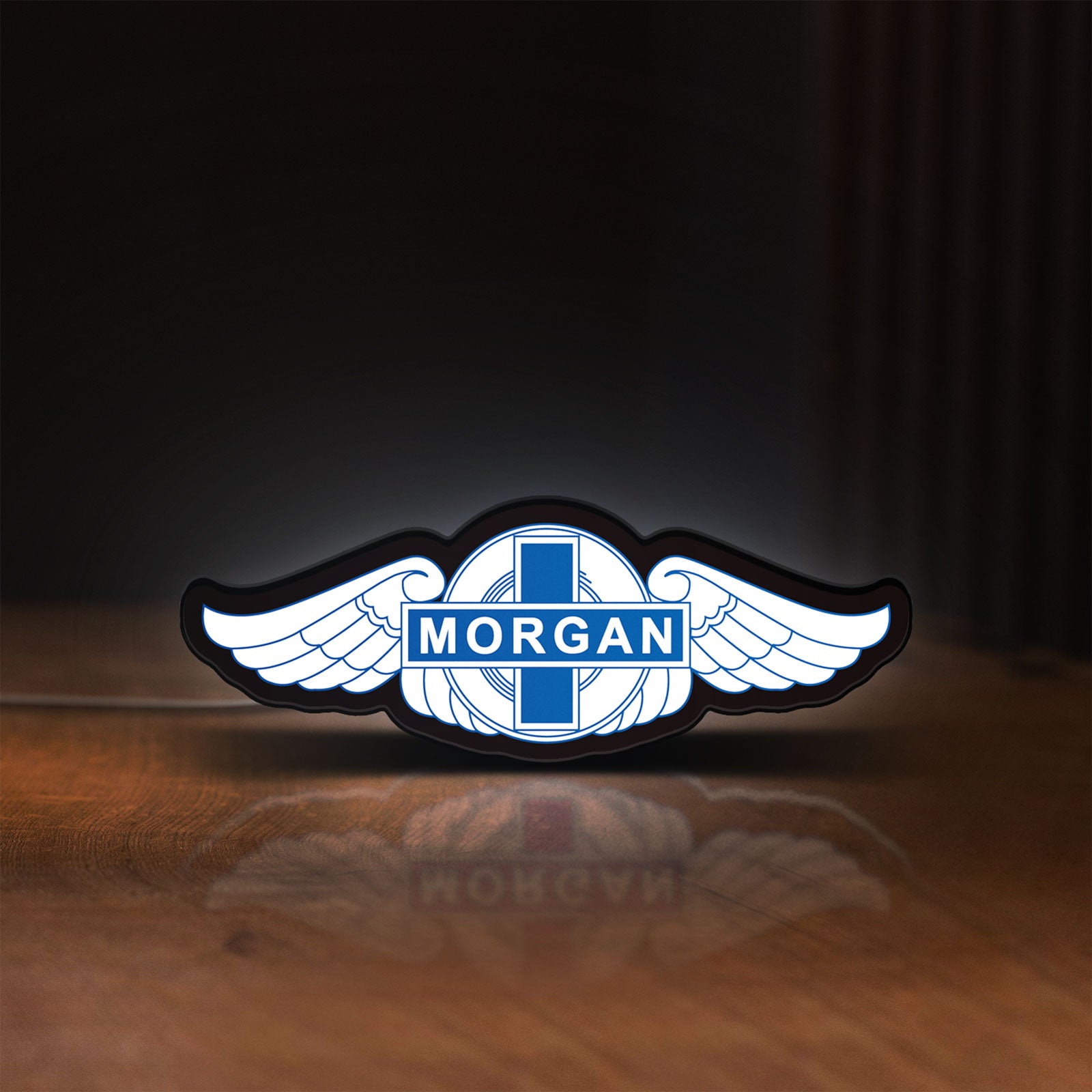 Front view of Morgan Motors LED lightbox sign glowing on a wooden desk