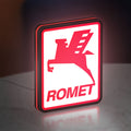 Romet Sign LED lightbox standing on a desk from an angled side view with red glow