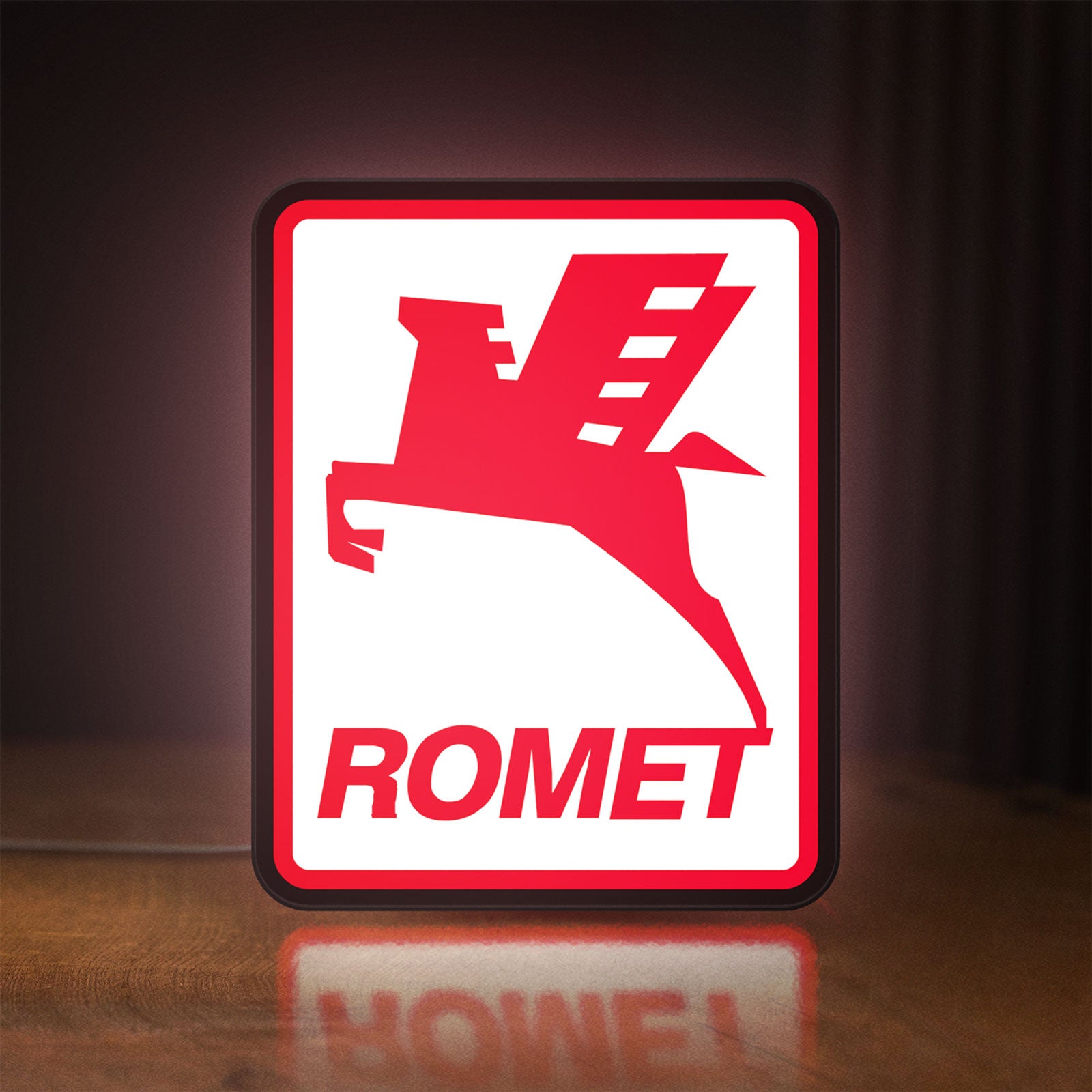 Front view of Romet Sign LED lightbox sign glowing on a wooden desk