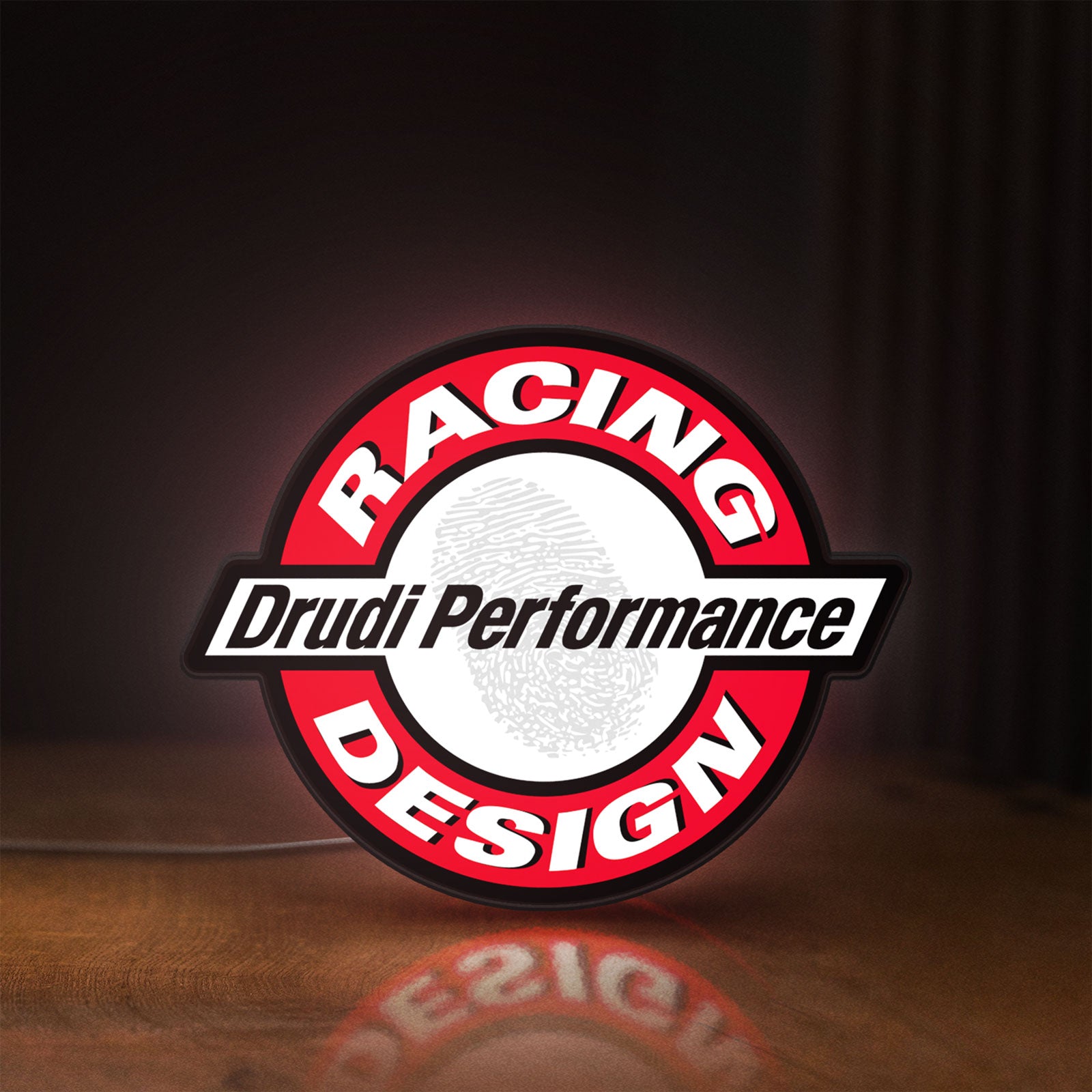 Front view of Drudi Performance LED lightbox sign glowing on a wooden desk