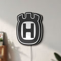 Unlit Husqvarna LED lightbox mounted on a wall in daylight