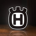 Front view of Husqvarna LED lightbox sign glowing on a wooden desk