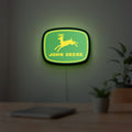 John Deere LED lightbox hanging on a room wall with soft green light