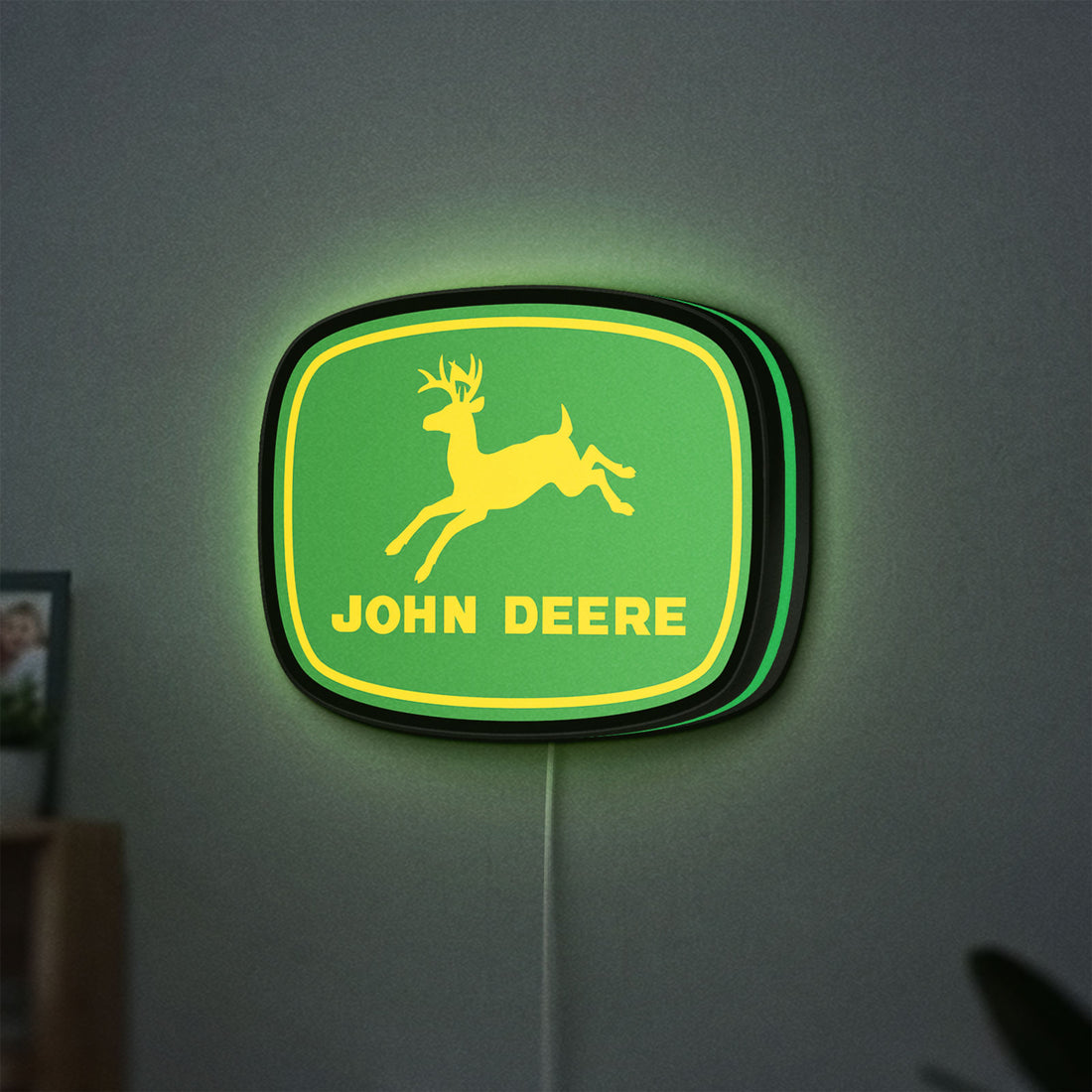 John Deere LED lightbox hanging on a wall with green glow