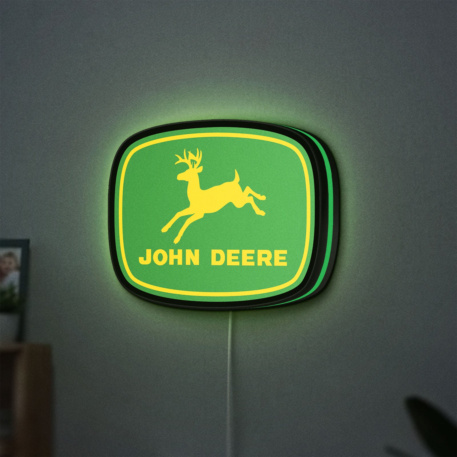 John Deere LED lightbox hanging on a wall with green glow