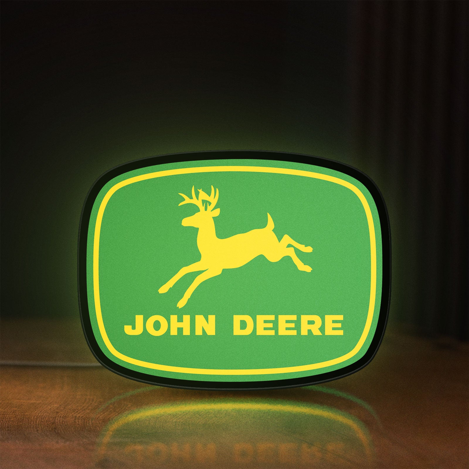 Front view of John Deere LED lightbox sign glowing on a wooden desk