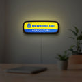 New Holland Agriculture LED lightbox hanging on a room wall with soft yellow light