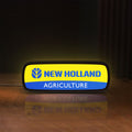 Front view of New Holland Agriculture LED lightbox sign glowing on a wooden desk