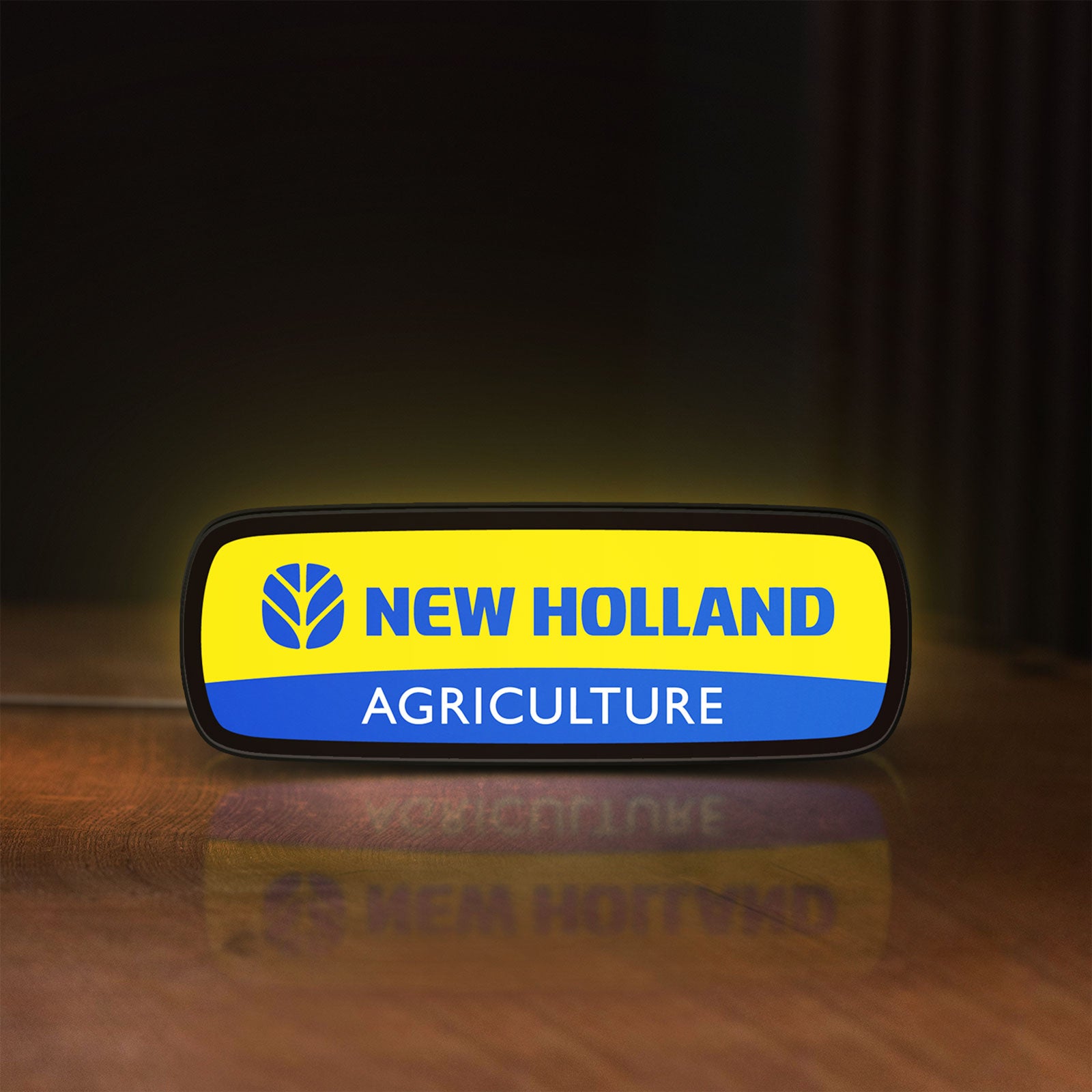 Front view of New Holland Agriculture LED lightbox sign glowing on a wooden desk