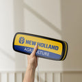 Unlit New Holland Agriculture LED lightbox held by hand to show size and details