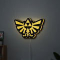 The Legend of Zelda Hyrulian Crest LED lightbox hanging on a wall with yellow glow