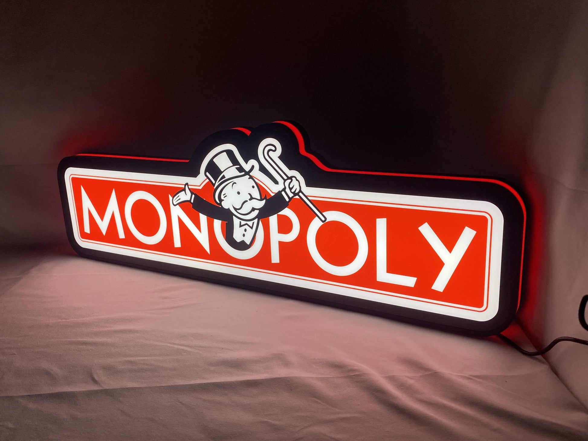 Illuminated angled view standing of Monopoly Money Bag Illuminated Sign in 60cm, unique wall art for desk and room decor
