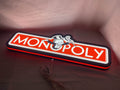Illuminated flat lay angled view of Monopoly Money Bag 3D LED Sign in 60cm, unique wall art for desk and room decor